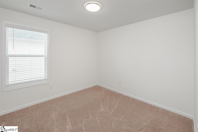 carpeted spare room with visible vents and baseboards