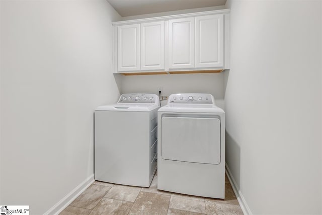 laundry area featuring separate washer and dryer, cabinet space, and baseboards