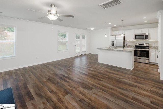 kitchen featuring stainless steel appliances, white cabinetry, open floor plan, hanging light fixtures, and a center island