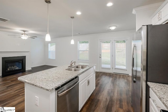 kitchen with pendant lighting, appliances with stainless steel finishes, white cabinetry, a sink, and an island with sink