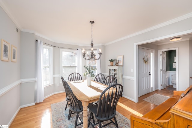 dining room with ornamental molding, light wood finished floors, and baseboards