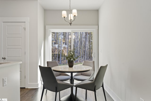 dining space featuring dark wood-style floors, a notable chandelier, and baseboards