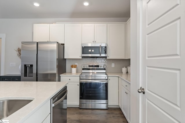 kitchen featuring light stone counters, dark wood-style flooring, white cabinets, appliances with stainless steel finishes, and tasteful backsplash