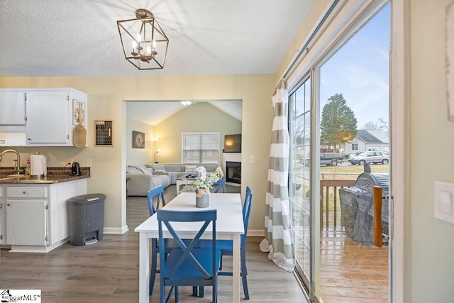 dining space featuring baseboards, a fireplace, an inviting chandelier, and wood finished floors