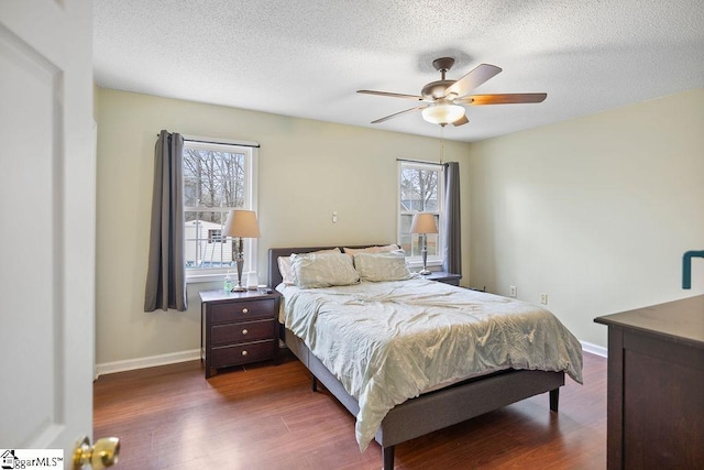 bedroom featuring dark wood-style floors, baseboards, and a textured ceiling