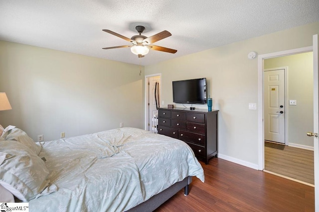 bedroom with ceiling fan, a textured ceiling, baseboards, and dark wood-type flooring