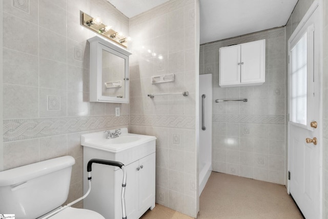 bathroom featuring toilet, vanity, and tile walls