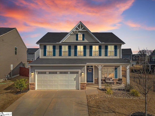 craftsman-style home with driveway, stone siding, an attached garage, and a porch