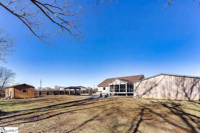 back of property with an outbuilding, a storage unit, a lawn, a gazebo, and a sunroom