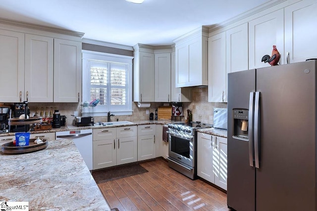 kitchen with white cabinets, dark wood-style floors, light stone counters, stainless steel appliances, and a sink