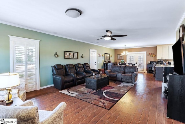 living area featuring dark wood-type flooring, ornamental molding, baseboards, and ceiling fan with notable chandelier