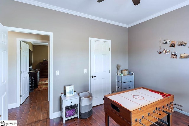 rec room featuring ceiling fan, dark wood-style flooring, baseboards, and crown molding