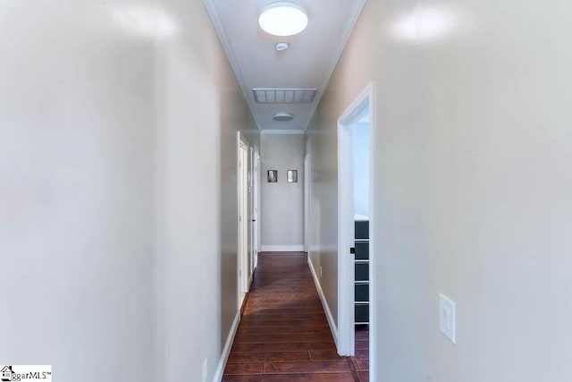 corridor with crown molding, visible vents, dark wood finished floors, and baseboards