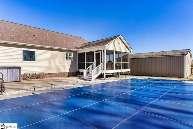 rear view of property featuring roof with shingles, a patio, a sunroom, crawl space, and a covered pool