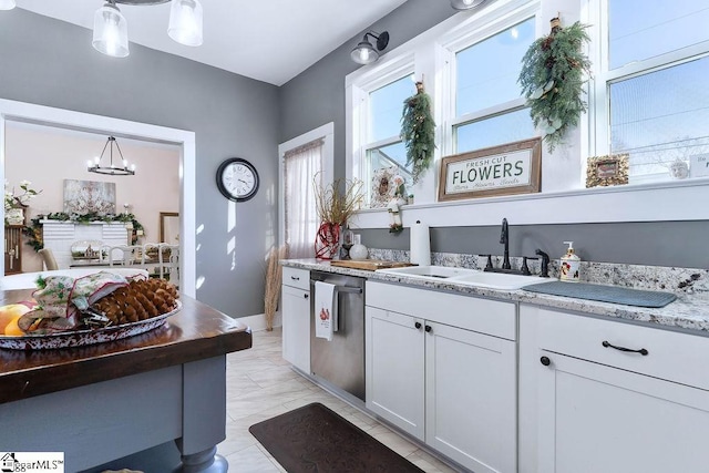 kitchen with white cabinets, hanging light fixtures, marble finish floor, stainless steel dishwasher, and a sink