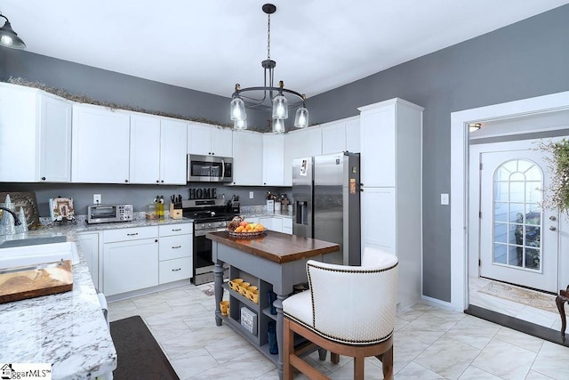 kitchen with pendant lighting, appliances with stainless steel finishes, dark stone counters, and white cabinets