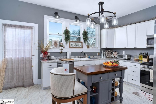 kitchen featuring appliances with stainless steel finishes, decorative light fixtures, white cabinetry, open shelves, and wooden counters