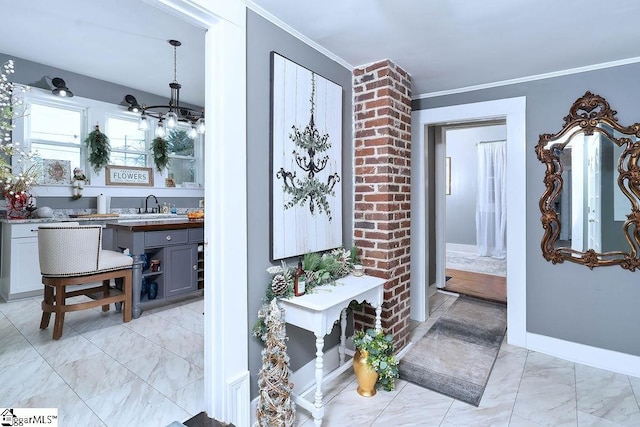 interior space with marble finish floor, a sink, crown molding, and baseboards