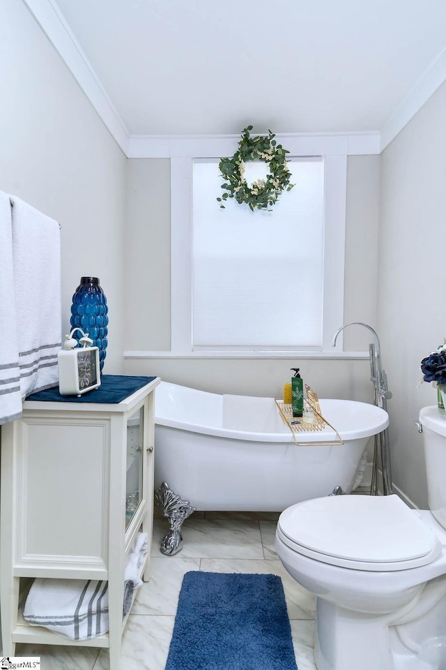 bathroom featuring ornamental molding, a freestanding tub, and toilet