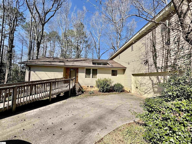 rear view of house with concrete driveway and a wooden deck