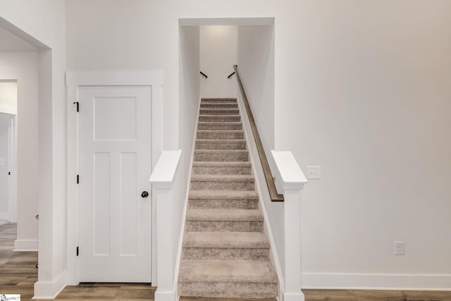 stairs featuring wood finished floors and baseboards