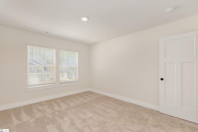 spare room featuring baseboards, visible vents, and light colored carpet