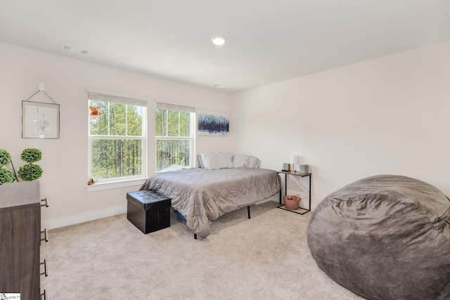 bedroom with baseboards, visible vents, and light colored carpet