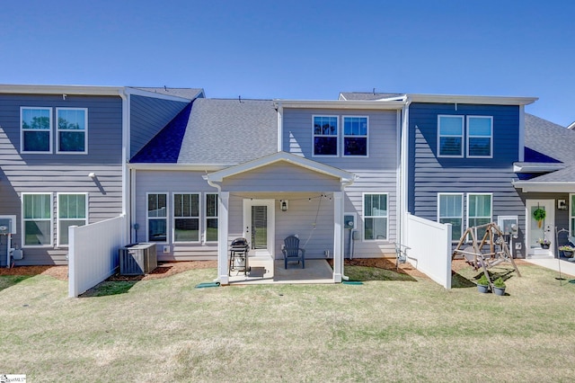 back of property with a yard, roof with shingles, a patio area, and central air condition unit