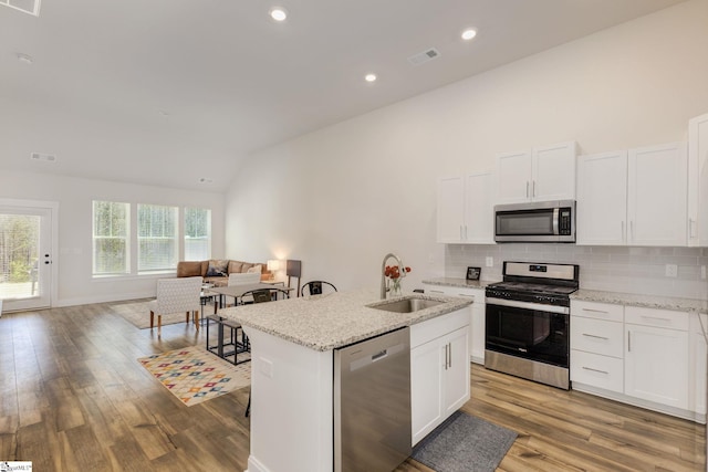 kitchen with appliances with stainless steel finishes, open floor plan, a kitchen island with sink, white cabinetry, and a sink