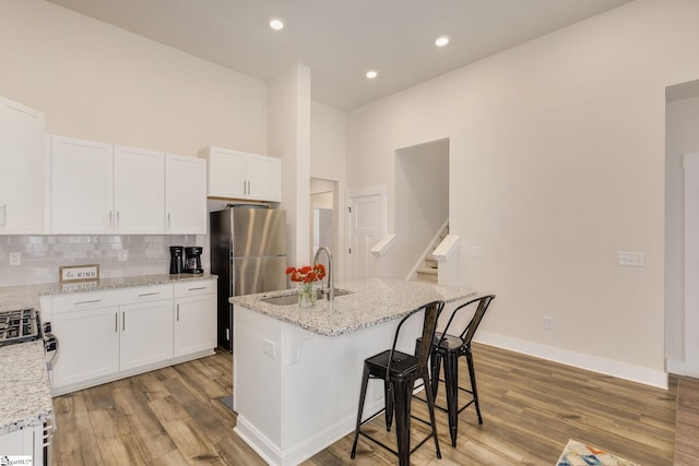 kitchen with a kitchen island with sink, white cabinets, and a sink