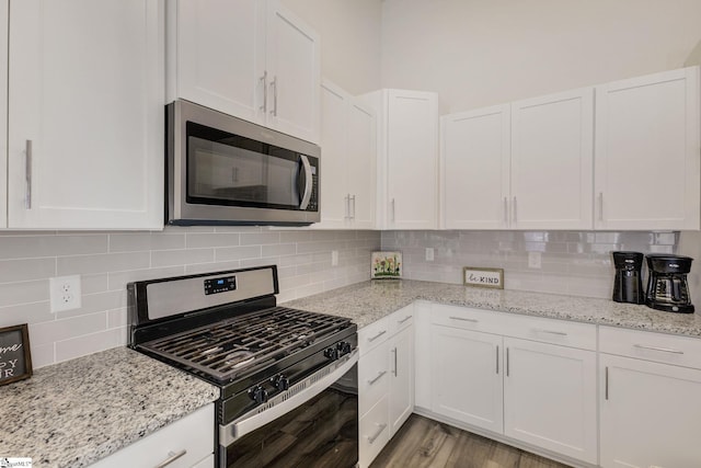 kitchen with appliances with stainless steel finishes, white cabinets, and backsplash