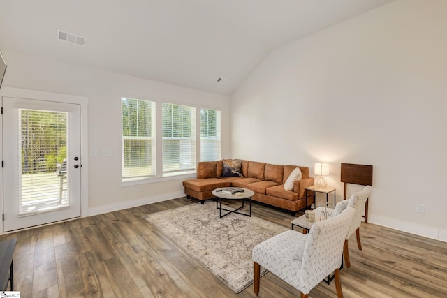 living area with baseboards, visible vents, vaulted ceiling, and wood finished floors