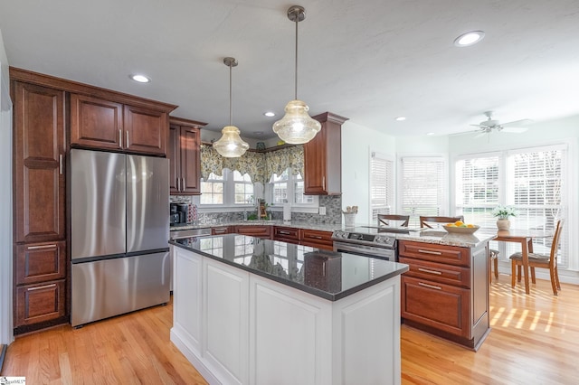 kitchen featuring hanging light fixtures, appliances with stainless steel finishes, dark stone counters, and a center island