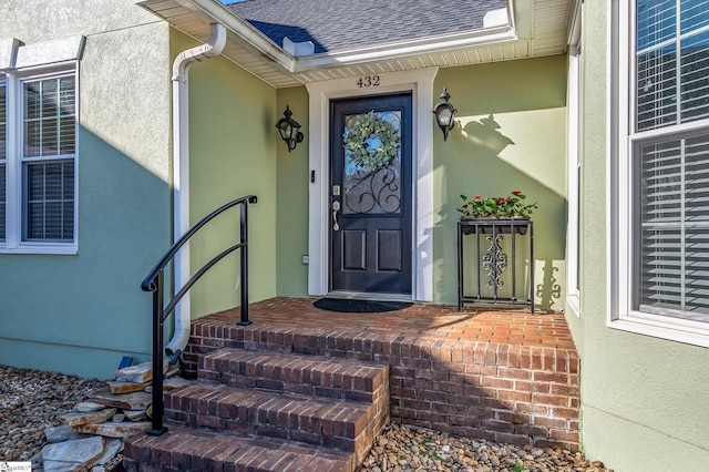 property entrance with roof with shingles and stucco siding