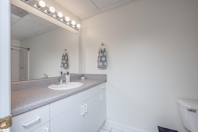 full bathroom with toilet, a paneled ceiling, vanity, baseboards, and walk in shower