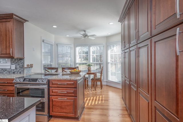 kitchen with tasteful backsplash, stone counters, double oven range, and light wood finished floors