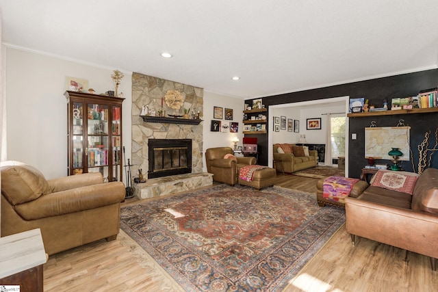 living area with a stone fireplace, recessed lighting, wood finished floors, and crown molding