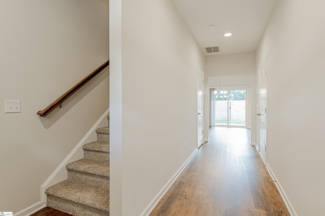 hall with baseboards, visible vents, stairway, wood finished floors, and recessed lighting