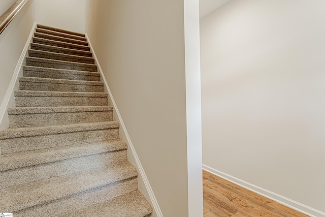 staircase featuring baseboards and wood finished floors