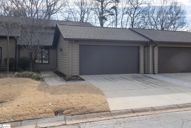 view of front facade featuring a garage, a shingled roof, and concrete driveway