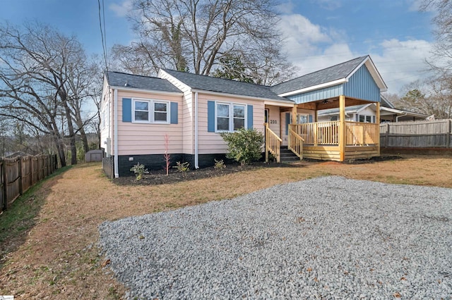 view of front facade with a porch, fence, and a shingled roof