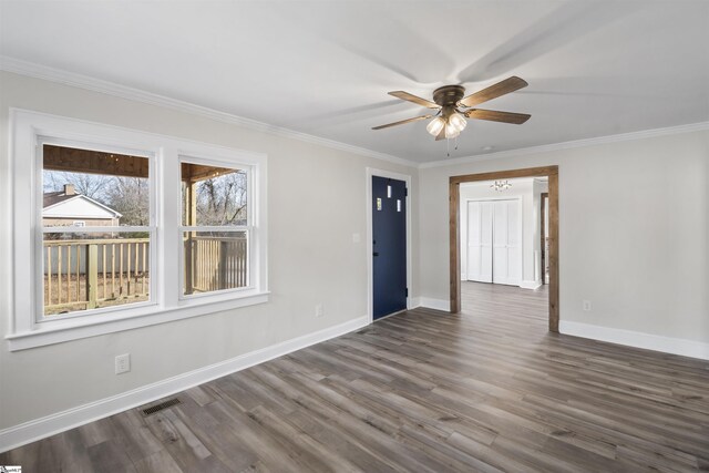 empty room with baseboards, visible vents, a ceiling fan, dark wood-style floors, and ornamental molding