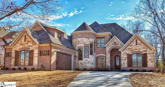 view of front of property with stone siding, brick siding, driveway, and an attached garage