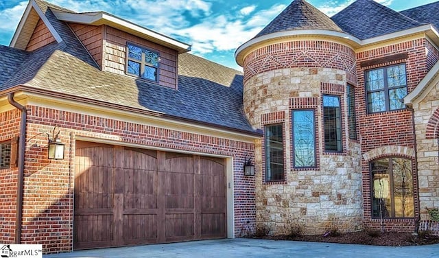 view of front facade with stone siding, brick siding, concrete driveway, and roof with shingles