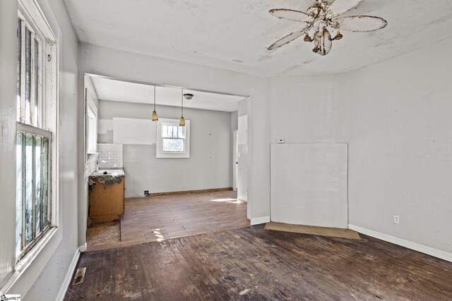 unfurnished living room with wood finished floors, visible vents, and baseboards