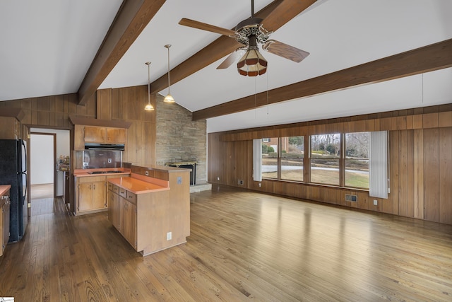 kitchen with wooden walls, wood finished floors, decorative light fixtures, a center island, and black appliances