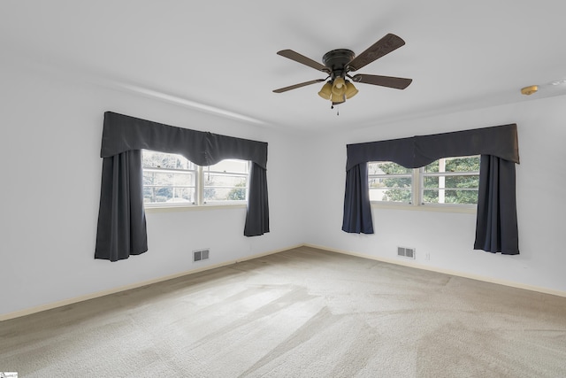 unfurnished room with plenty of natural light, visible vents, and carpet flooring