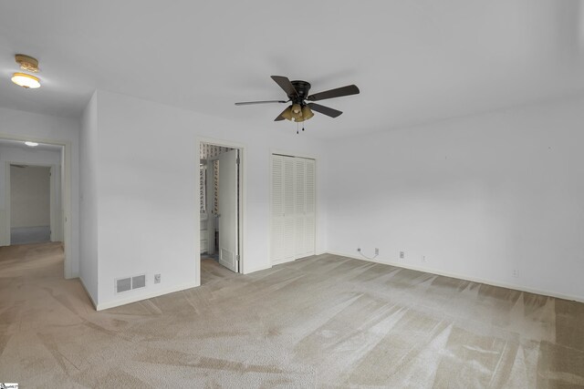 spare room featuring a ceiling fan, visible vents, light carpet, and baseboards