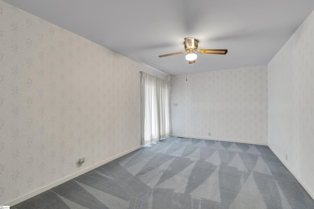 carpeted empty room featuring baseboards, ceiling fan, and wallpapered walls