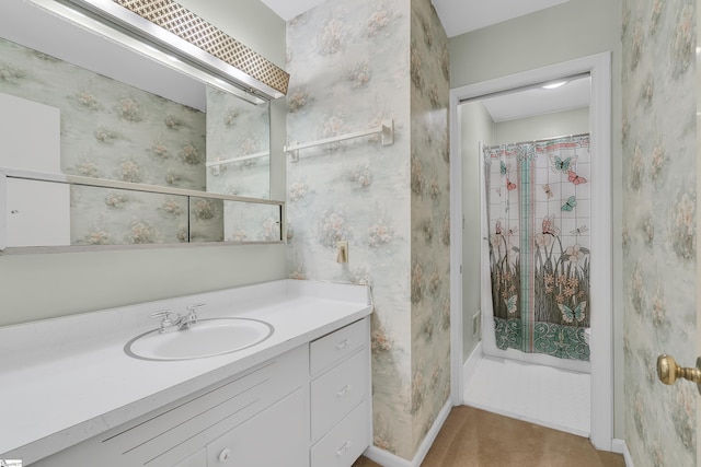 bathroom with a shower with curtain, vanity, baseboards, and wallpapered walls